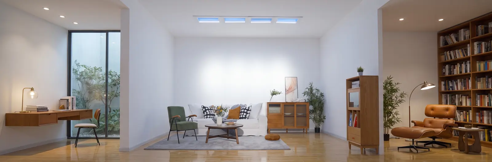 An open living room with no side windows, lit by a row of four Yeelight skylights in the ceiling that show blue sky
